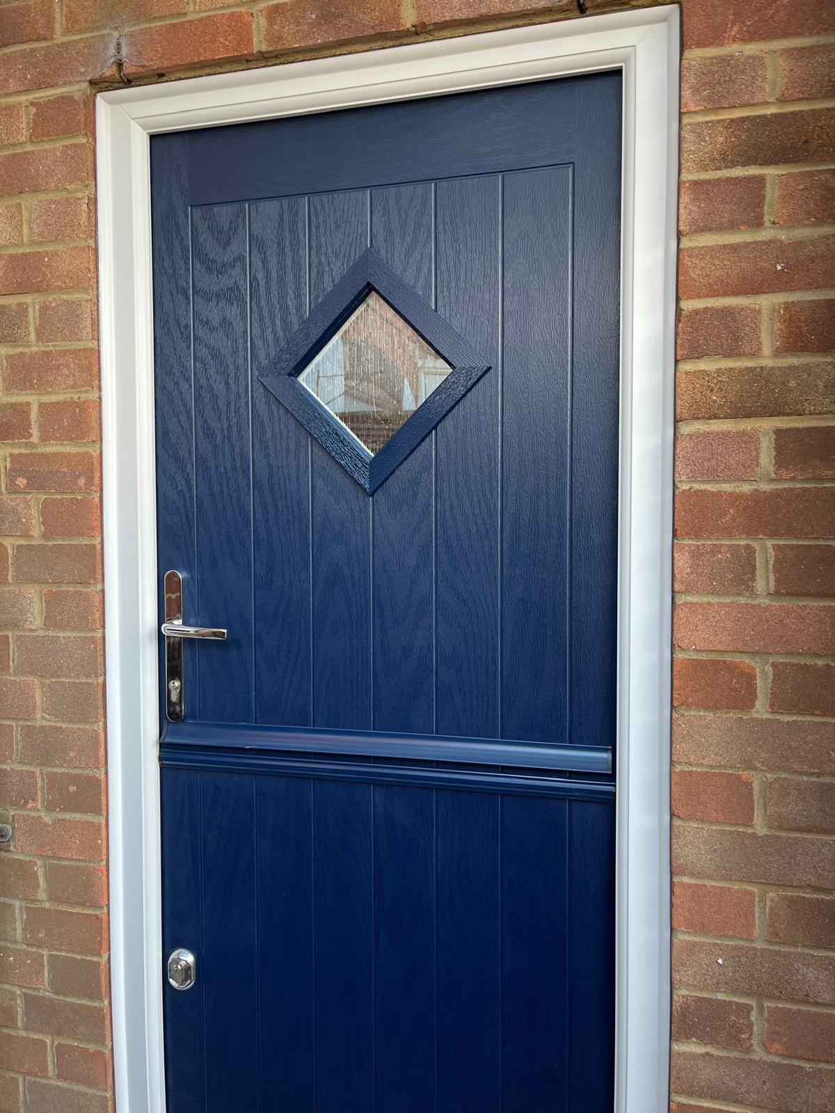 Blue composite stable door with diamond glass panel installed in brick home